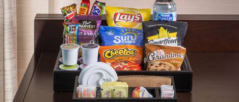 A tray of assorted snacks and beverages on a wooden table.