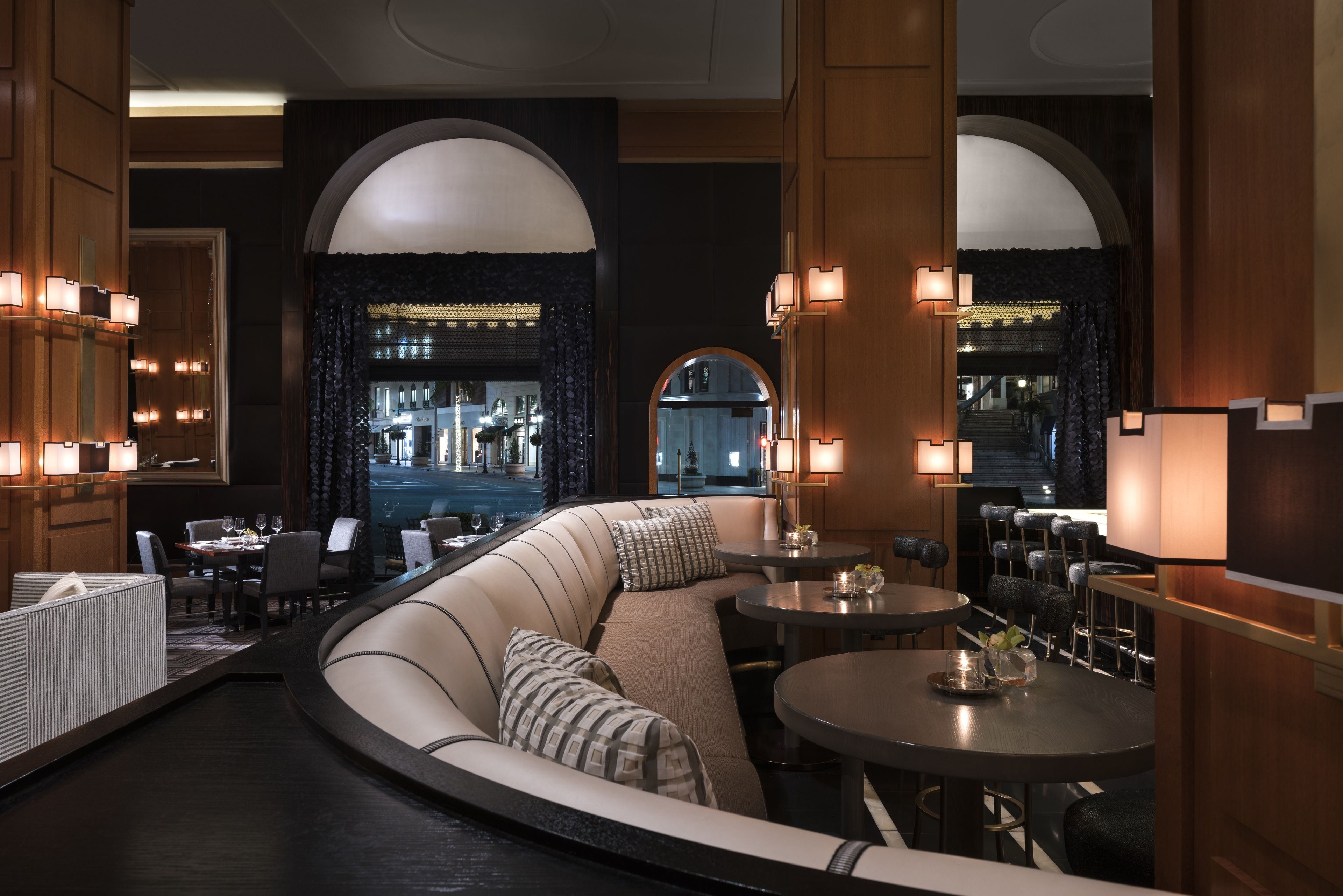 A modern restaurant with a curved seating area, round tables, and warm lighting.