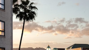 A sunset view of a street lined with buildings, including a hotel with a terrace set up for an event.
