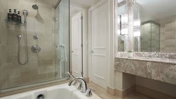 A modern bathroom with a glass-enclosed shower, a large bathtub, and a marble countertop with a sink.