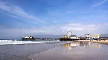 A beach with a pier, a Ferris wheel, and a roller coaster.