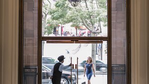 A grand entrance with a chandelier, a man holding a set of keys, and a woman in a blue dress standing at the door. - Beverly Wilshire, Beverly Hills, A Four Seasons Hotel (Beverly Hills)