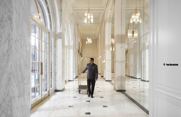 Un pasillo de hotel con paredes de mármol, candelabros y un cartel que indica 'The Ballroom'.