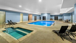 A hotel pool area with a small pool, lounge chairs, and a table. - Quality Inn Fort Dodge (Fort Dodge)