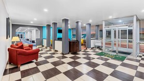 A hotel lobby with a checkered floor, a reception desk, a red sofa, and a glass door entrance. - Quality Inn Fort Dodge (Fort Dodge)