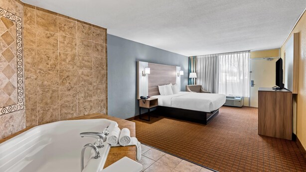 A hotel room with a large bathtub, a bed, a desk, and a television. - Quality Inn Fort Dodge (Fort Dodge)
