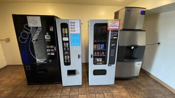 Trois distributeurs automatiques proposant des boissons et des en-cas, un distributeur d’eau et un panneau indiquant « SEULEMENT LES PIÈCES DE 25 CENTIMES » pour certains articles.