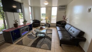 A modern living room with a sofa, chairs, a coffee table, and a TV. - Reliance Inn (Wausau)