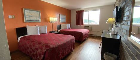 A hotel room with two beds, a desk, a TV, and a window with a view.