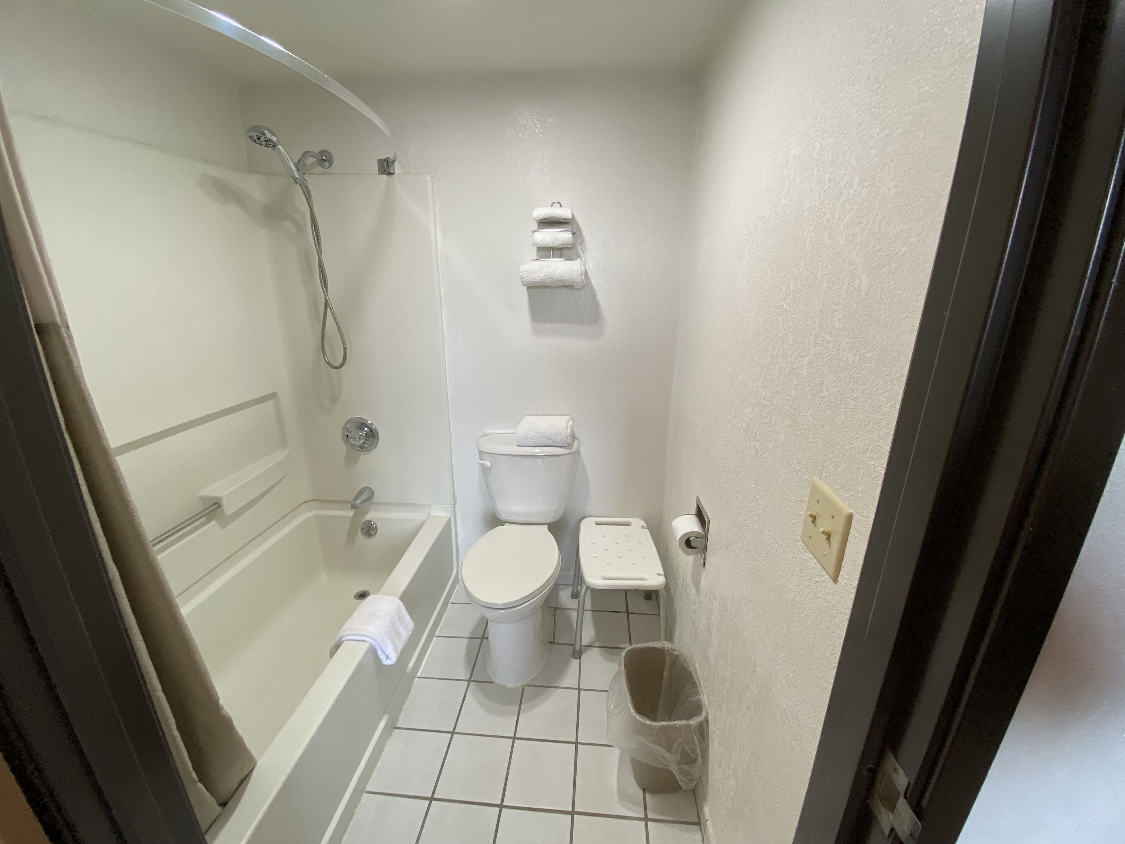 Et lille badeværelse med badekar, toilet og bruser.