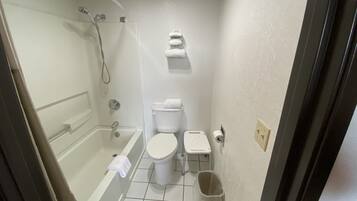 Et lille badeværelse med badekar, toilet og bruser.