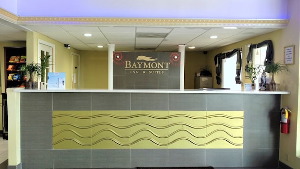 Uma receção com o logotipo Baymont Inn & Suites, um candelabro e um extintor.
