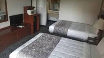 Une chambre d’hôtel avec deux lits, une commode, un téléviseur et un miroir.