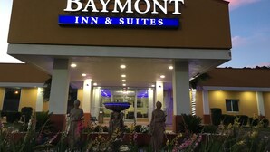 Edifício do Baymont Inn & Suites com uma placa grande, uma fonte e estátuas na frente.