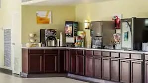 Uma cozinha equipada com geladeira, micro-ondas, cafeteira e diversos eletrodomésticos.