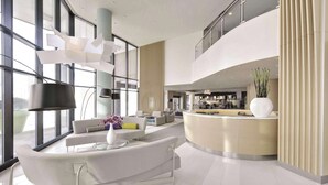 A modern hotel lobby with a curved reception desk, a seating area with sofas, and large windows offering views of the city. - Radisson Blu Toronto Downtown (Toronto)