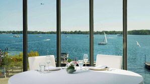 Een tafel gedekt voor twee personen met uitzicht op een meer en boten.