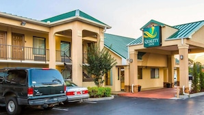 A Quality Inn hotel with a green roof, a covered entrance, and a parking lot with two cars. - Quality Inn Dahlonega Near University (Dahlonega)