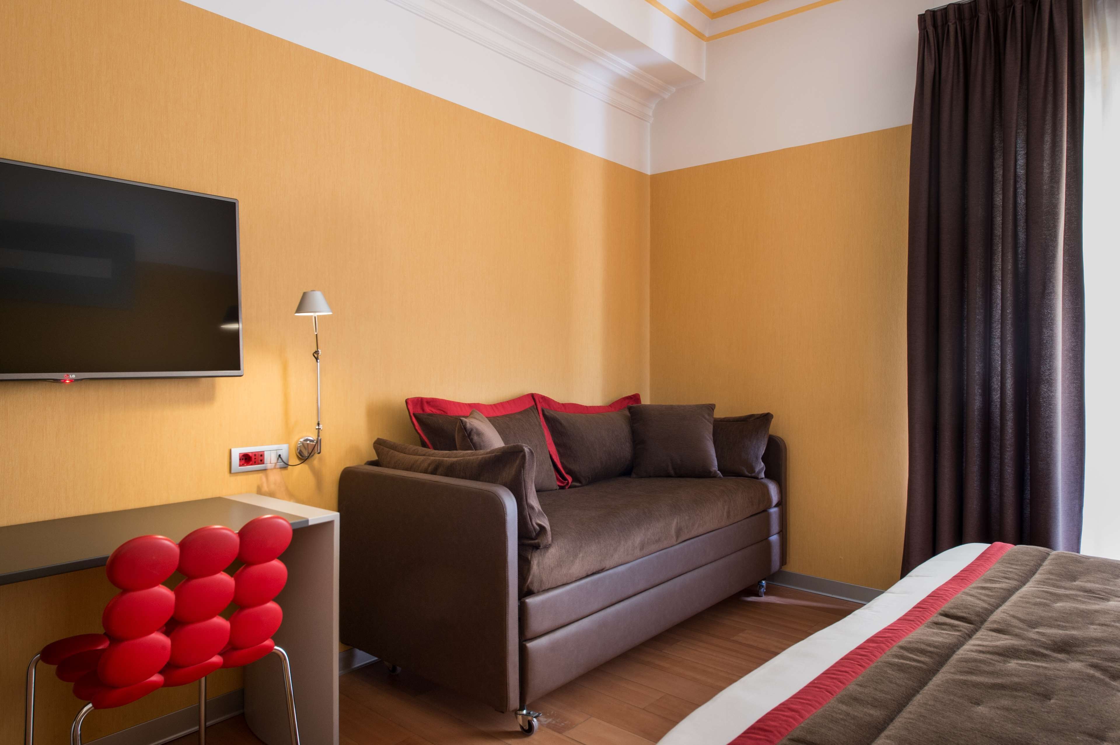 Une chambre d’hôtel avec un canapé, une télévision, une lampe et un lit.
