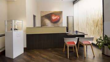 A reception area with a reception desk, two chairs, a glass display case, and a large wall art piece.