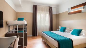 Quarto de hotel com beliche, uma escrivaninha e uma cadeira.