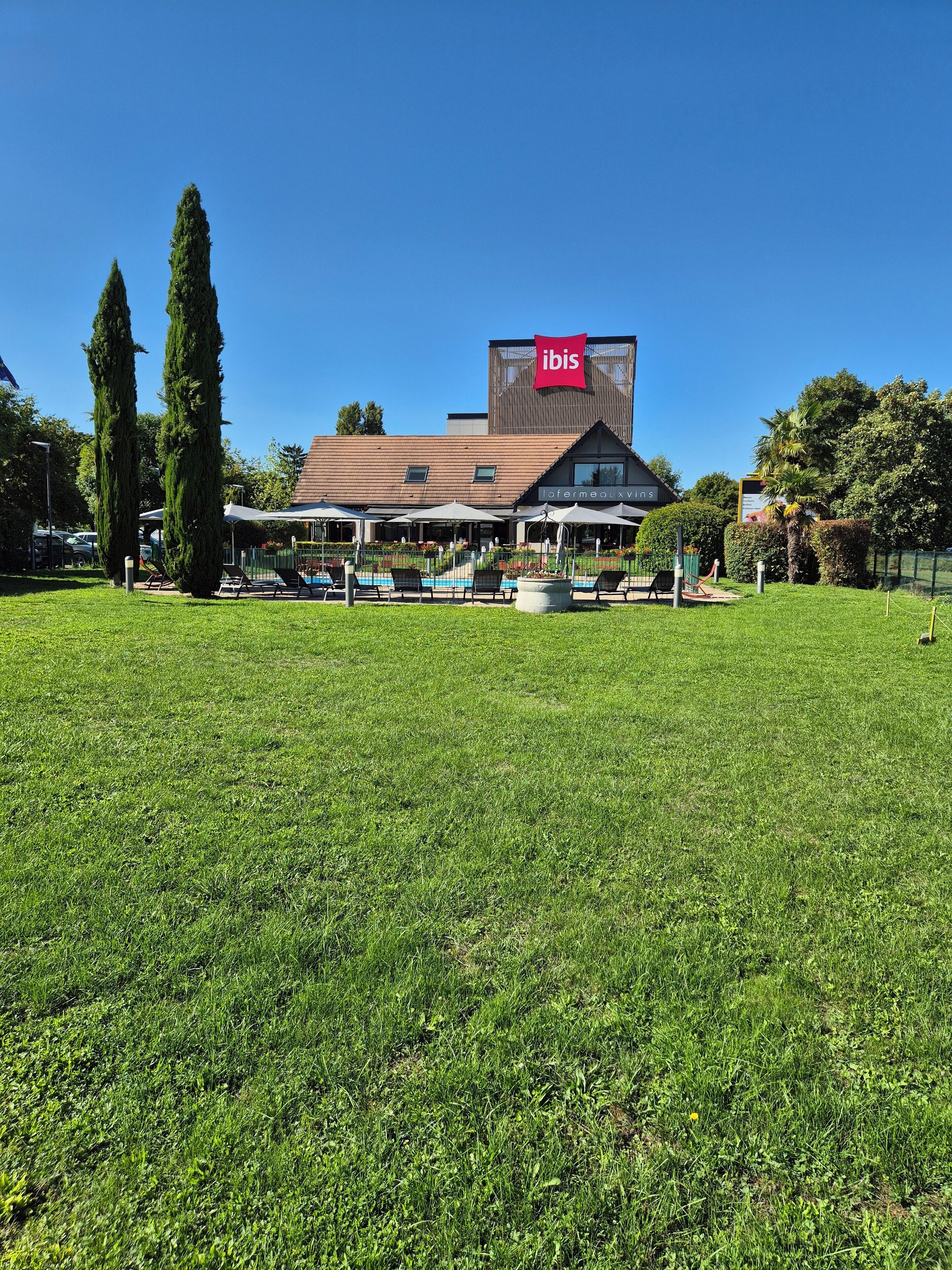 A hotel with a large lawn, outdoor seating, and a pool area.