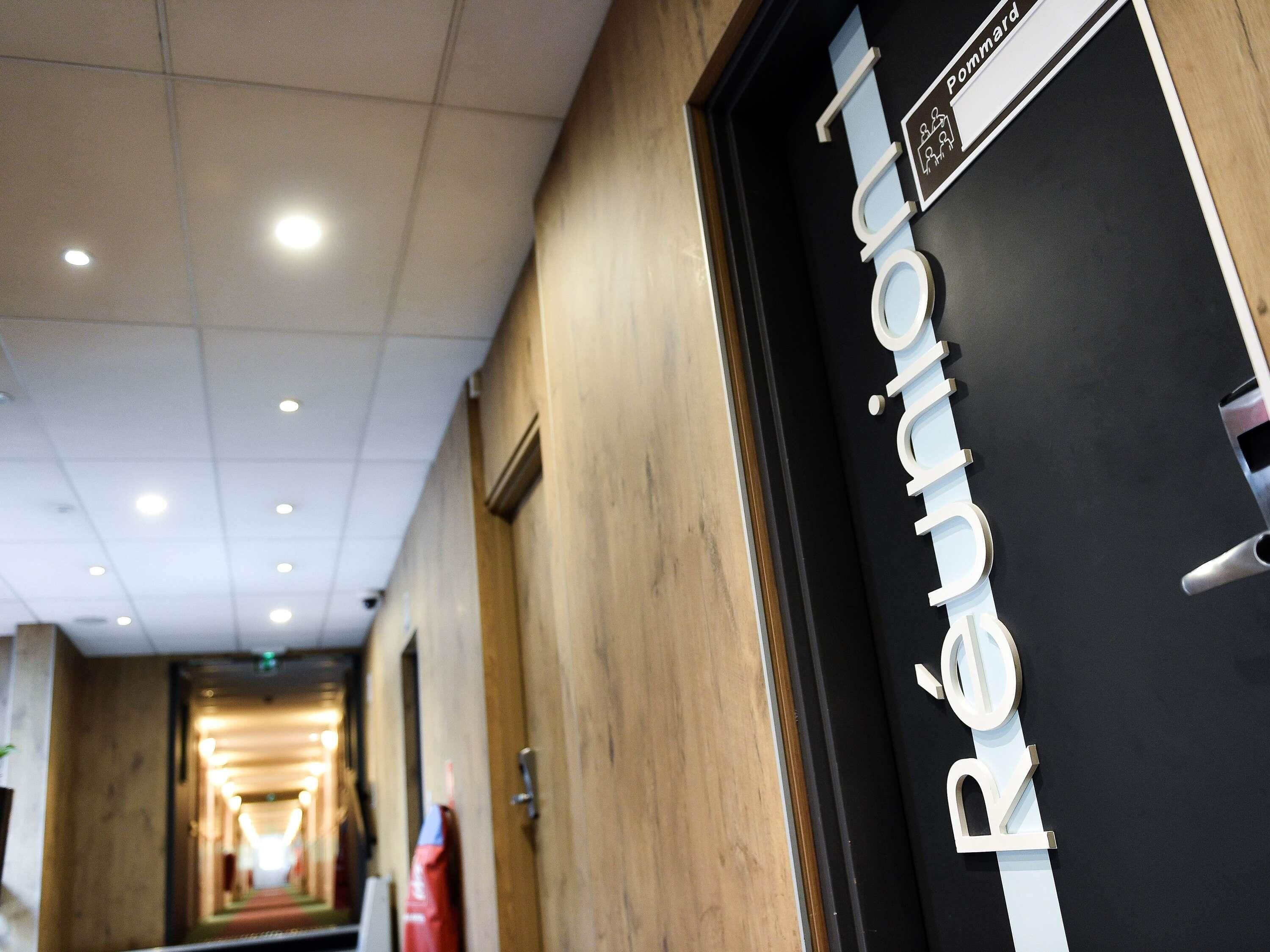 A hotel corridor with a reception desk labeled 'Réunion' and a sign indicating 'Check-in' with a number.