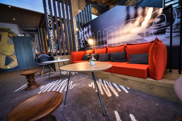 A modern lounge area with a red sofa, a round table, and a wooden coffee table. - ibis Beaune La Ferme Aux Vins (Beaune)