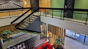 Un vestíbulo de hotel de varios niveles con una zona de estar, una escalera y un restaurante.