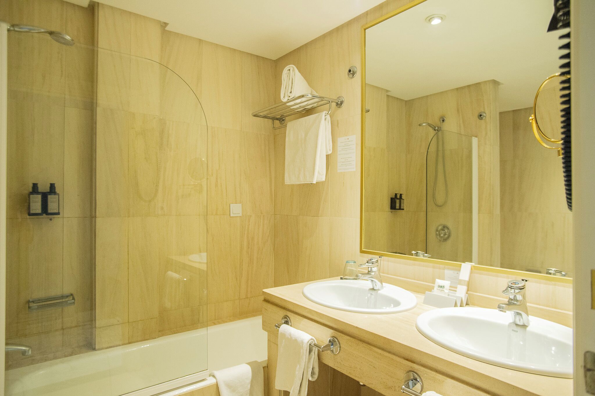 A modern bathroom with two sinks, a large mirror, and a shower area.