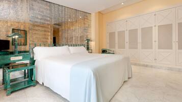 A spacious bedroom with a large bed, a nightstand, a lamp, and a wardrobe with louvered doors.