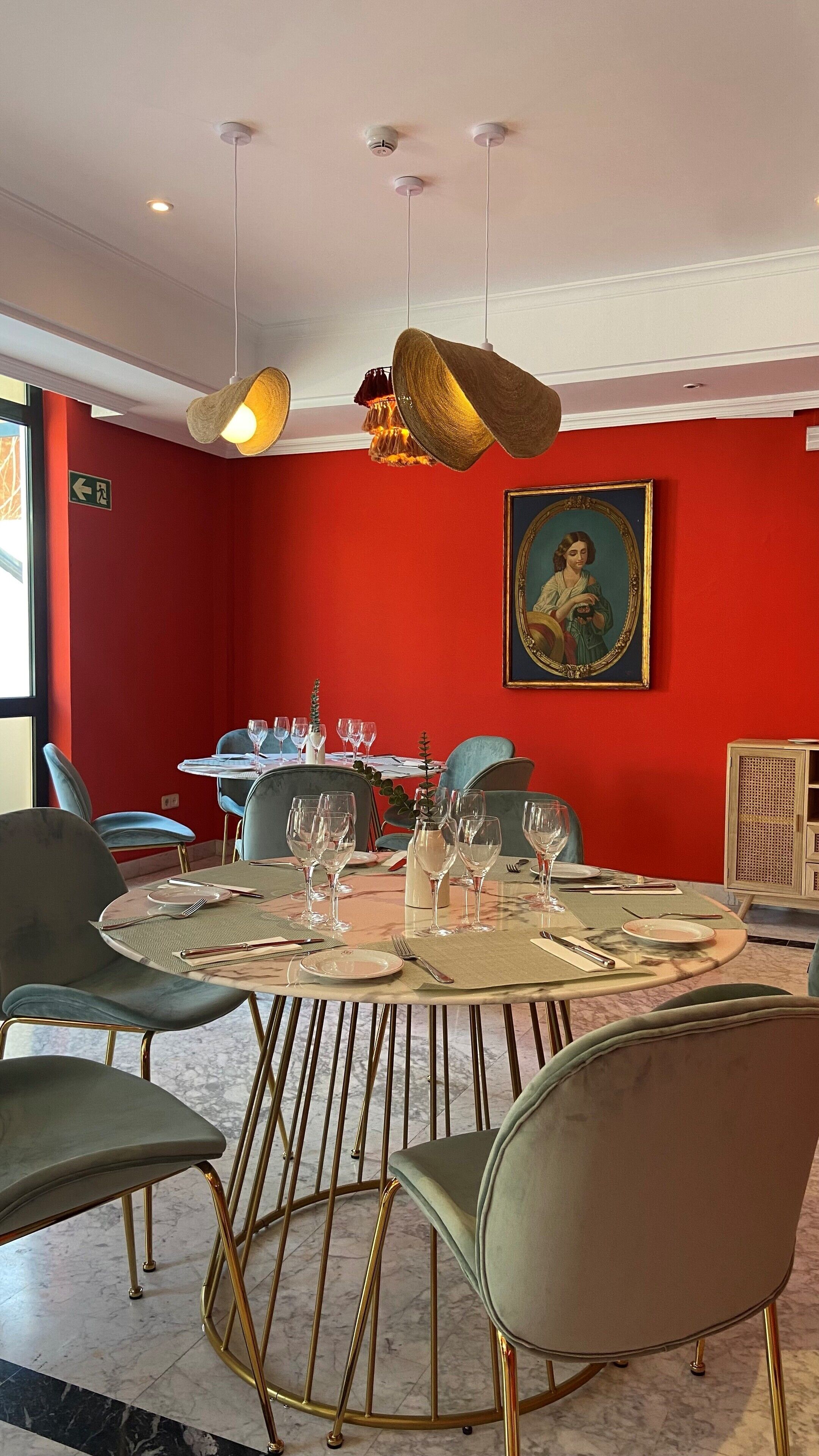 Un espace repas avec des tables rondes, des chaises et un tableau accroché au mur.