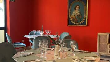 Un espace repas avec des tables rondes, des chaises et un tableau accroché au mur.