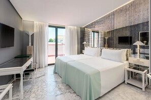 A hotel room with a bed, a desk, a chair, a TV, and a window with curtains.
