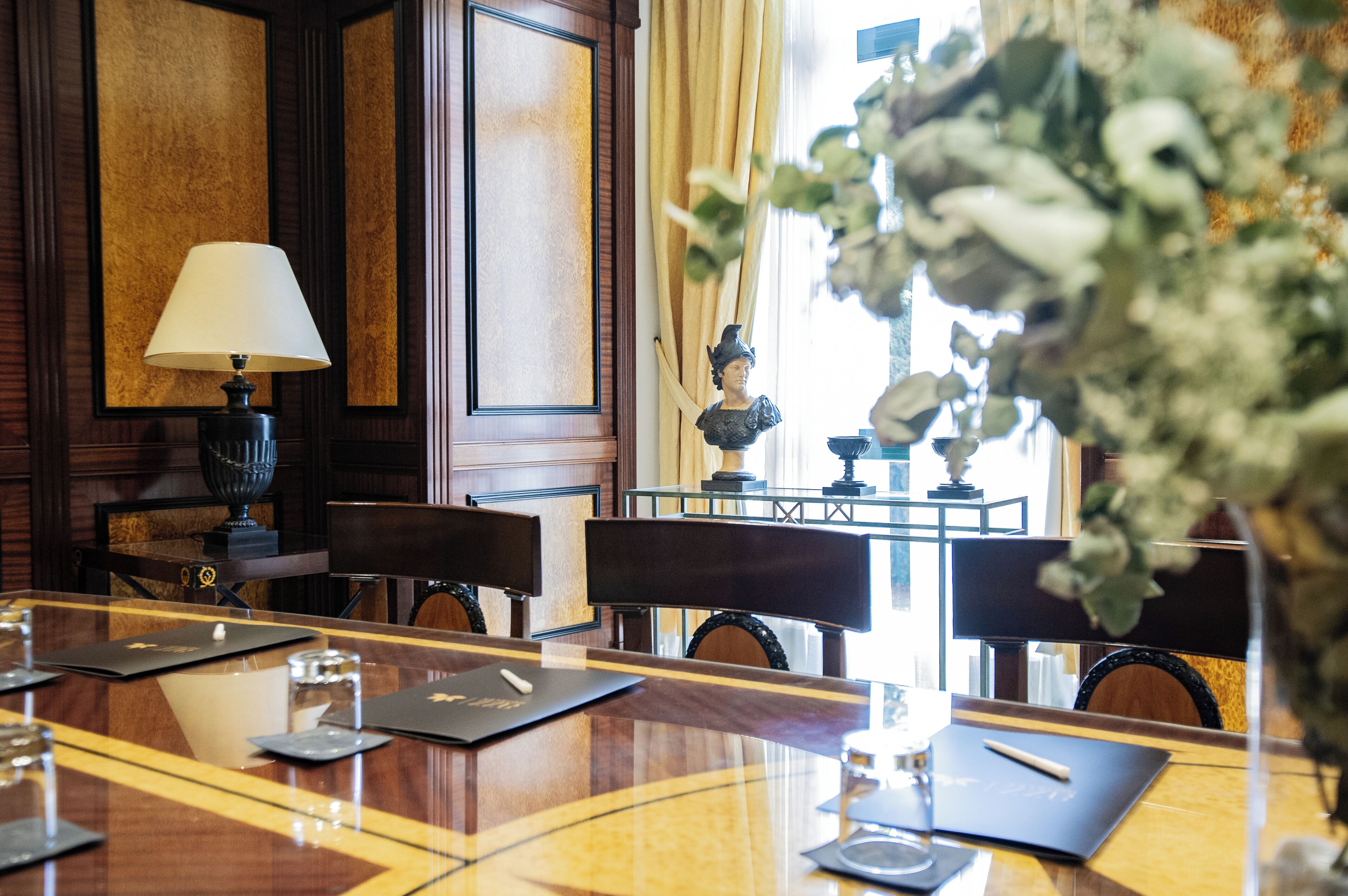 Un salón de conferencias con una larga mesa, sillas, una lámpara y una estatua.