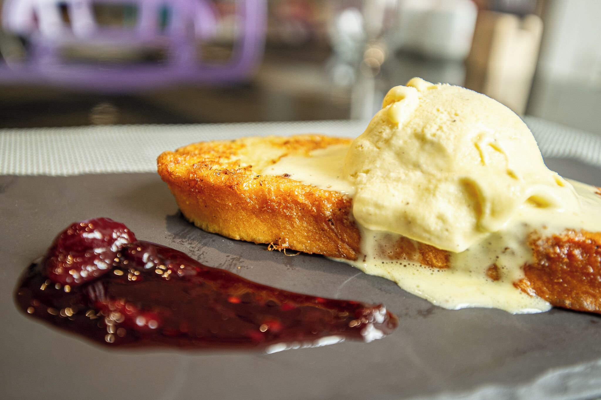 Ein Dessertteller mit einer Toastscheibe, belegt mit Eis und Beerensauce.