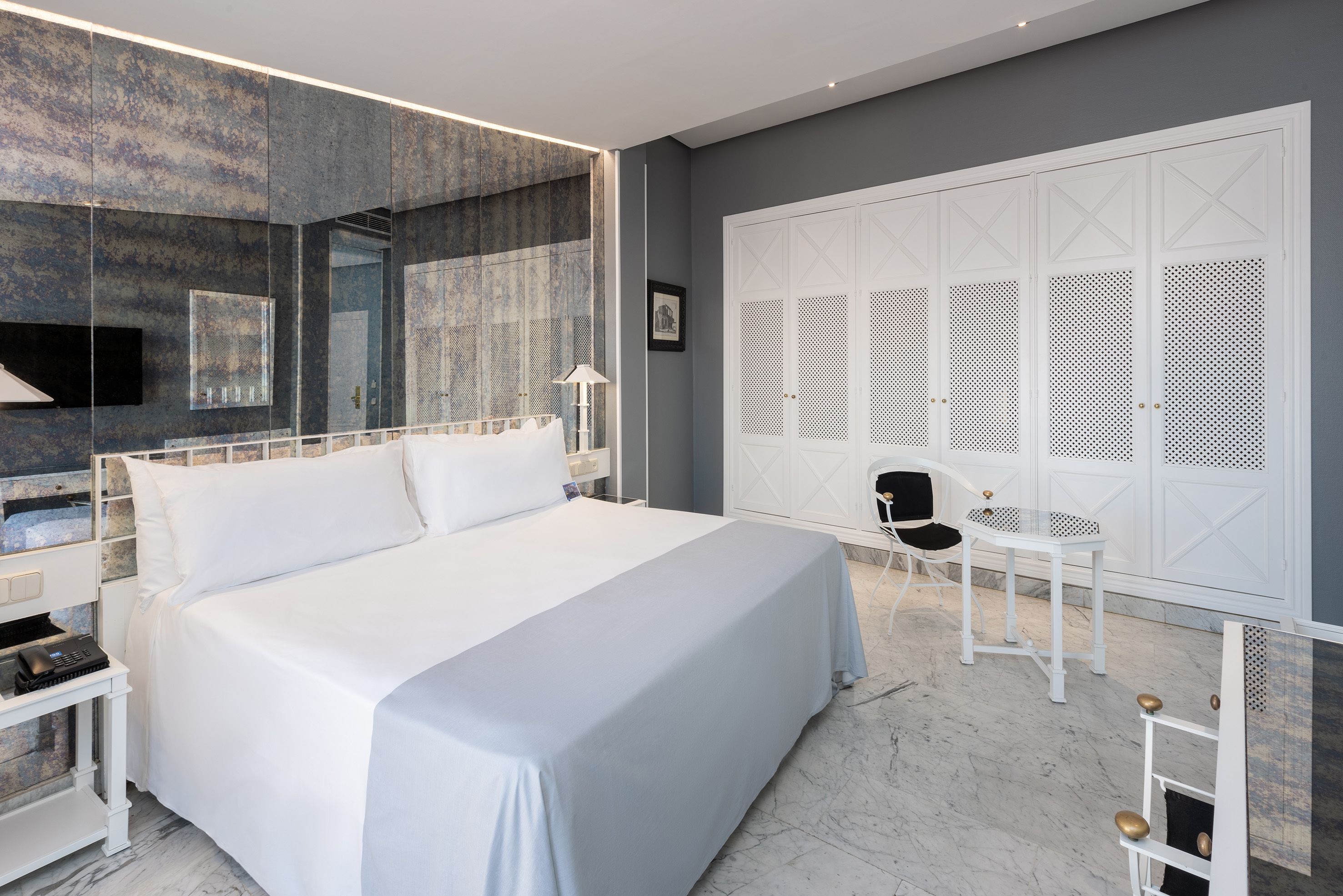 Una habitación de hotel moderna con una cama grande, un escritorio, una silla y un armario de diseño único.