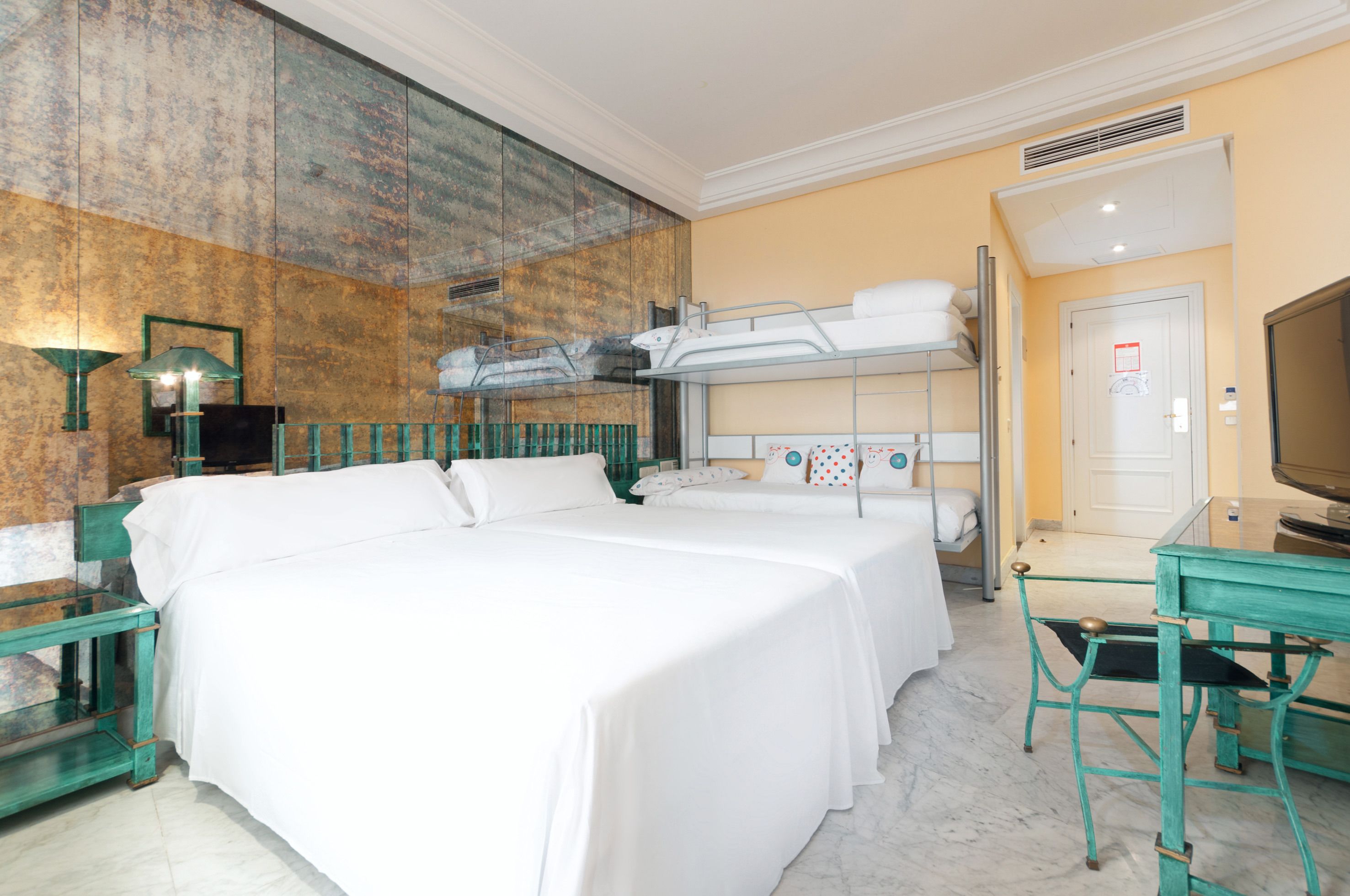 Habitación de hotel con dos camas, televisión, escritorio y espejo.