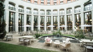 A courtyard with outdoor seating, a fountain, and large windows. - AZZ Mérida Medea (Merida)