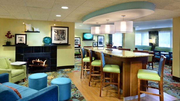 A hotel lobby with a fireplace, seating area, bar, and a television.