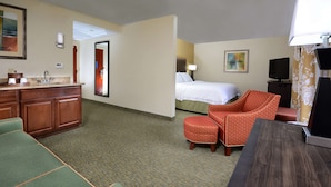 A hotel room with a bed, a desk, a chair, a TV, and a bathroom area.