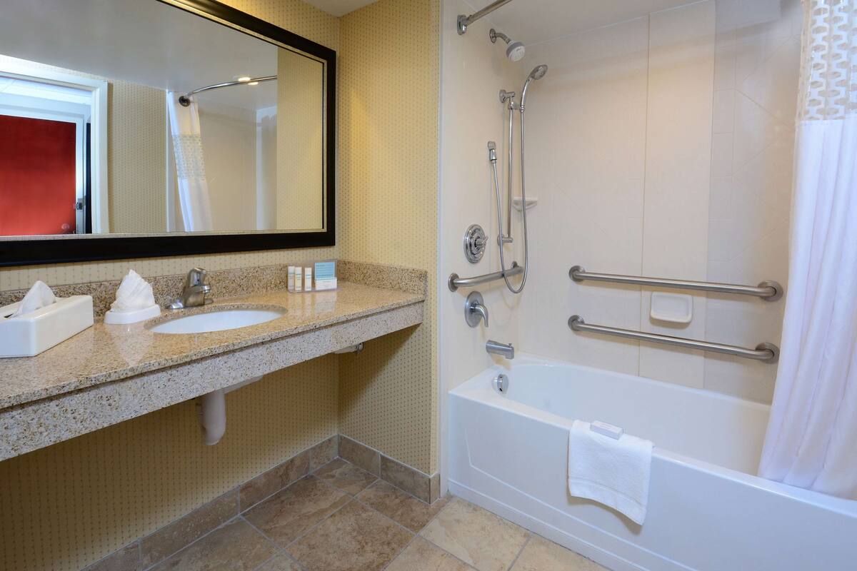 A bathroom with a sink, mirror, shower, and bathtub.