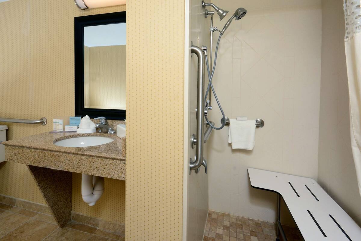 A bathroom with a sink, mirror, and shower.