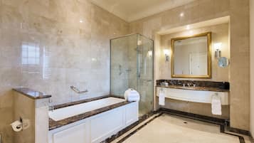 A modern bathroom with a glass-enclosed shower, a large bathtub, and a vanity with a mirror and towel rack.