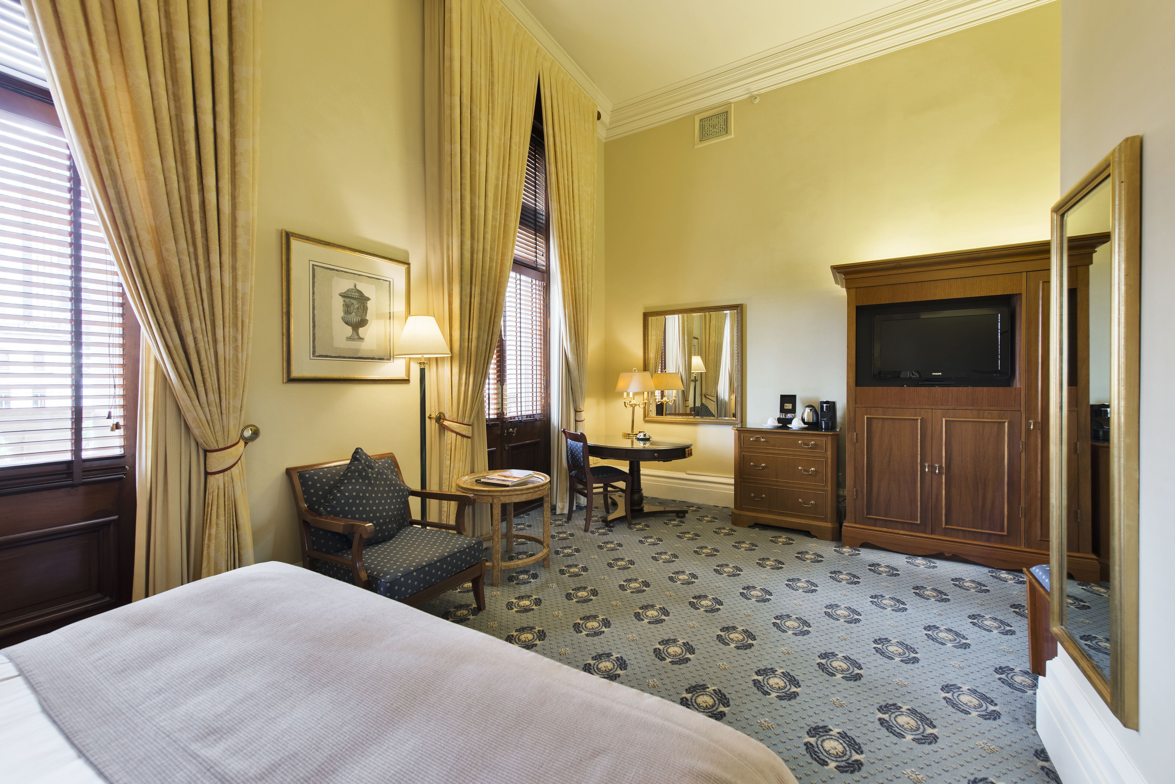 Una habitación de hotel con cama, escritorio, silla, cómoda y televisión.