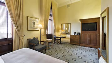 Una habitación de hotel con cama, escritorio, silla, cómoda y televisión.