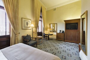 Una habitación de hotel con cama, escritorio, silla, cómoda y televisión.
