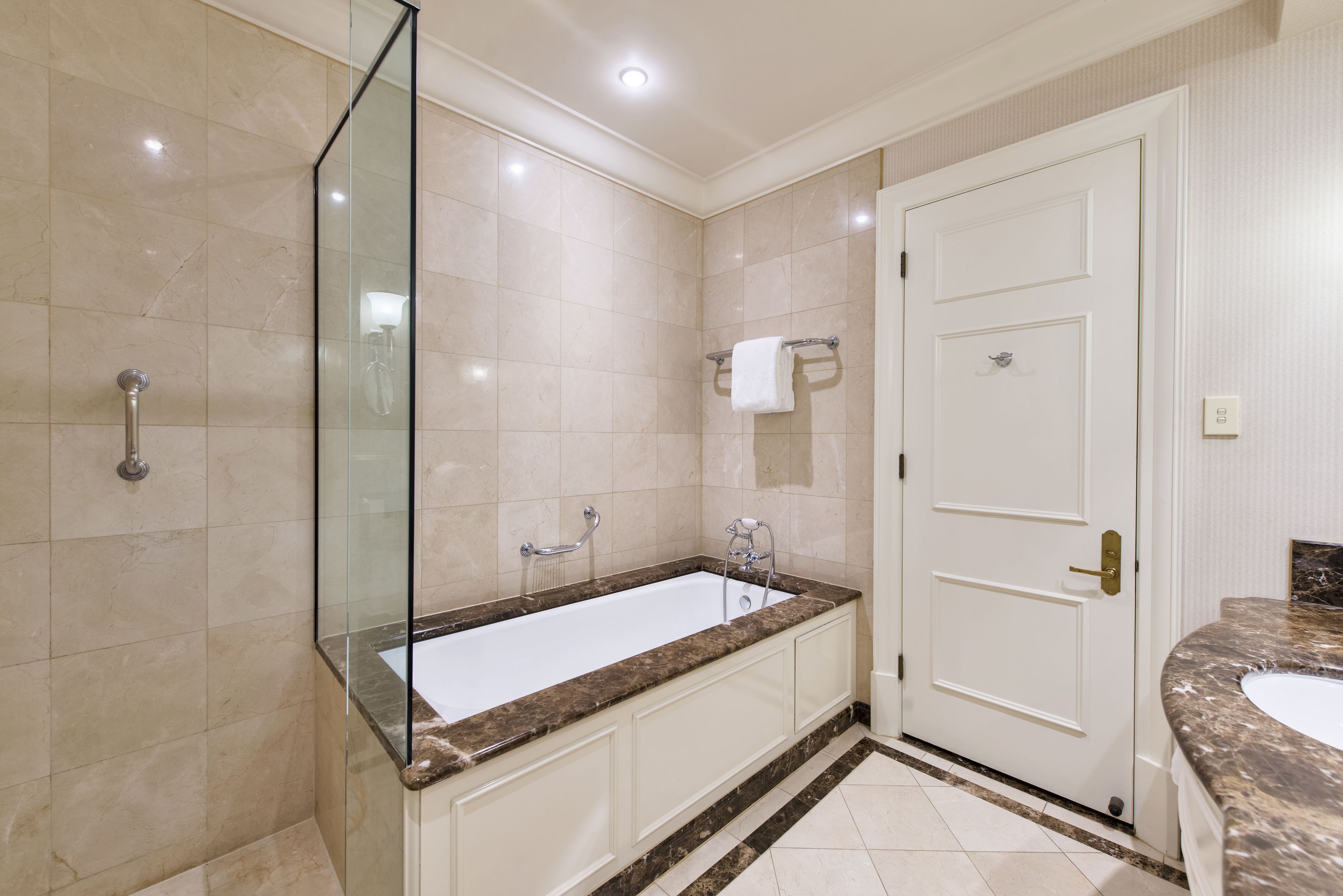 A modern bathroom with a large bathtub, a glass shower enclosure, and a white door.