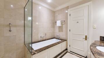 A modern bathroom with a large bathtub, a glass shower enclosure, and a white door.