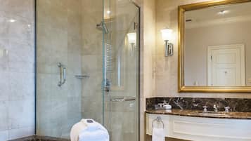 Un baño moderno con ducha de vidrio, un espejo grande y tocador de mármol.